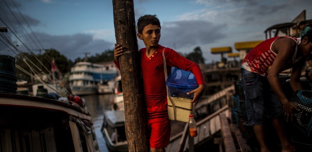 Antonio, 12, se equilibra nas docas enquanto vende comida em Santana, próximo a Macapá